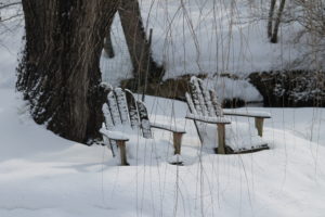Adirondack chairs by pond in snow