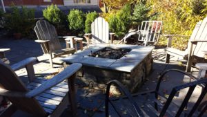 A custom wood-burning fire pit made of natural stone is perfect for fall nights!