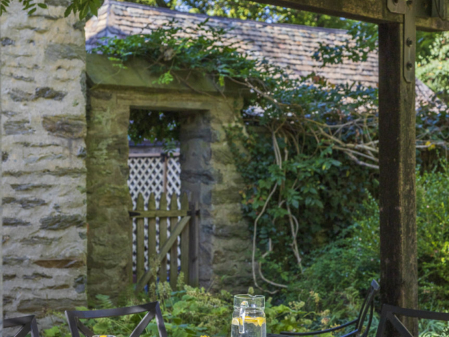 On the other side, the seating area overlooks an elegant stone wall covered in vines.