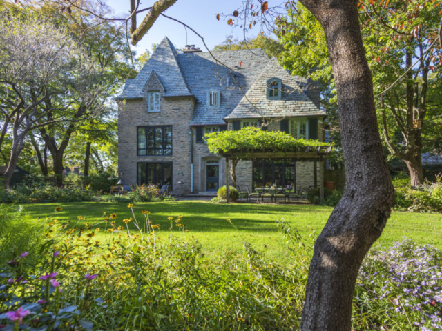A French-style stone house with a formal lawn encircled by naturalistic perennial beds