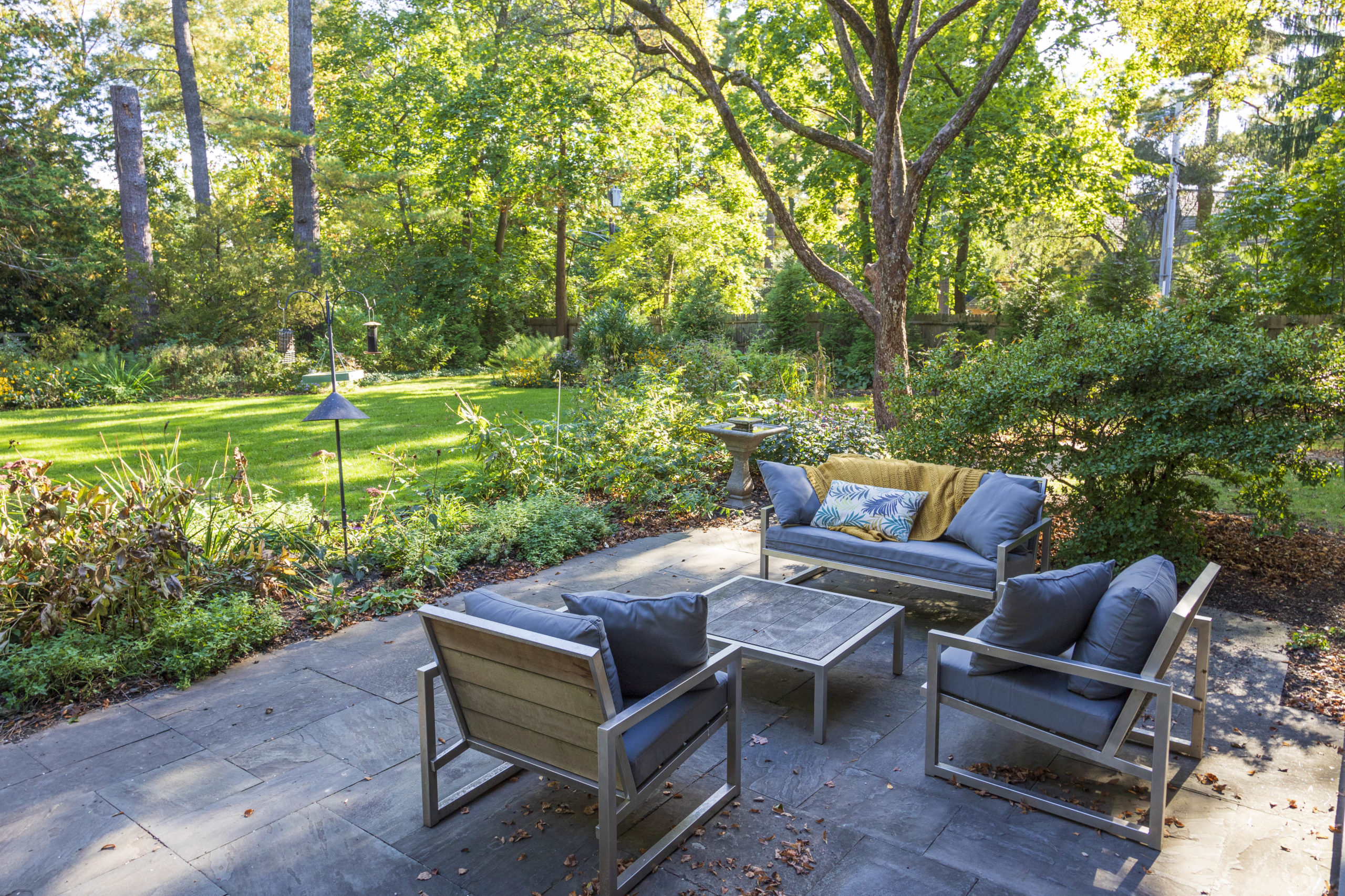A relaxed seating area on a flagstone patio has views of a formal lawn and colorful, naturalistic garden beds.