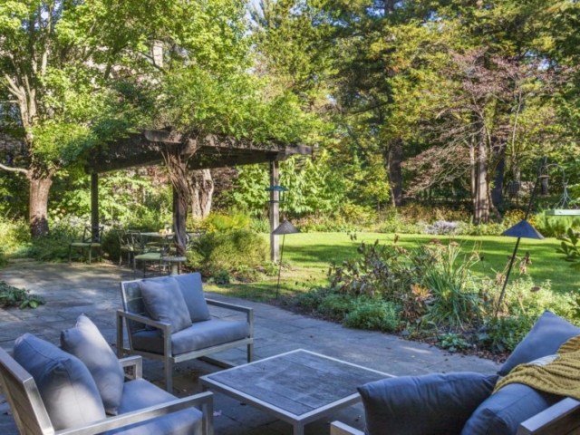 Thriving perennial beds provide privacy and calm to seating areas on an elegant stone patio.