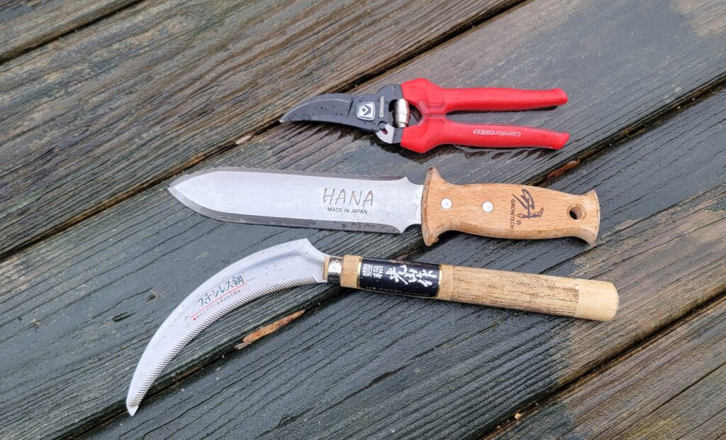 Pruners, a soil knife, and a hand sickle are useful garden tools.