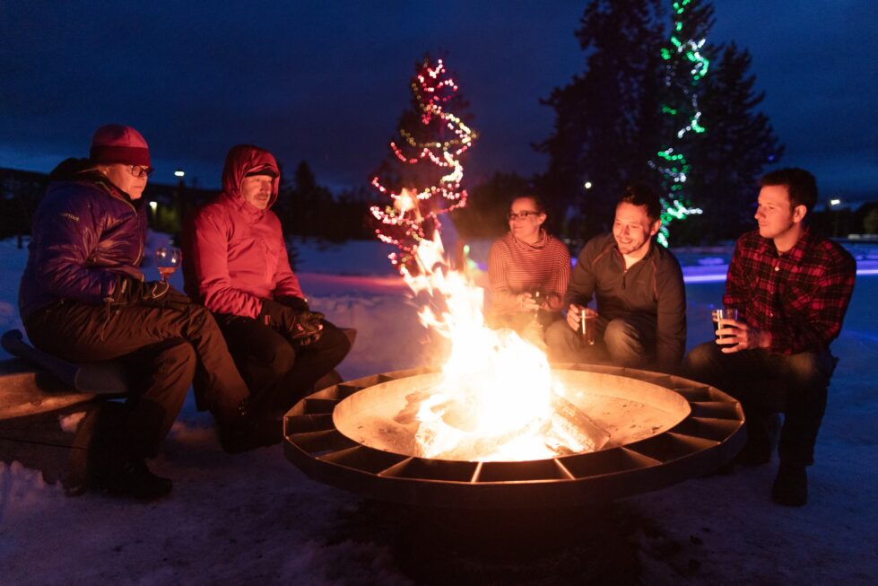 People sitting around a fire pit enjoying drinks.